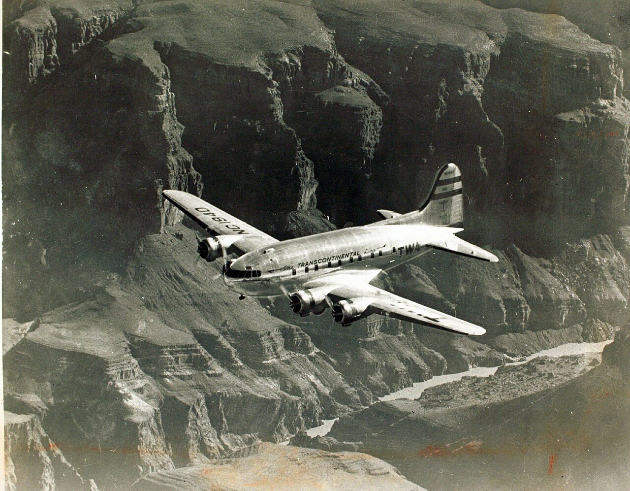 A TWA Boeing 307 Stratoliner in flight over mountains