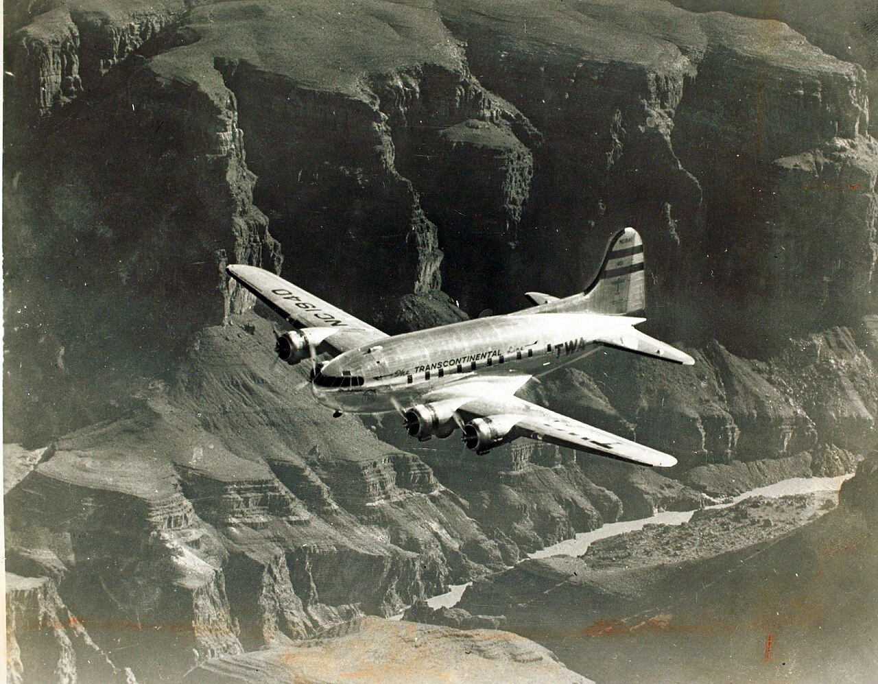 A TWA Boeing 307 Stratoliner in flight over mountains